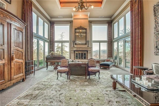 sitting room with crown molding, a large fireplace, a tray ceiling, carpet flooring, and a high ceiling