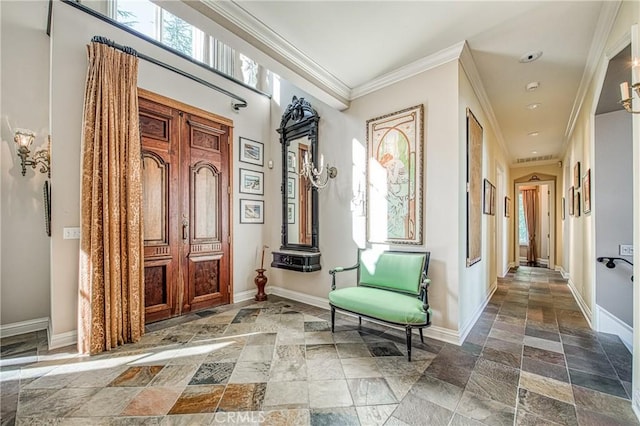 hall featuring crown molding, baseboards, and stone tile flooring