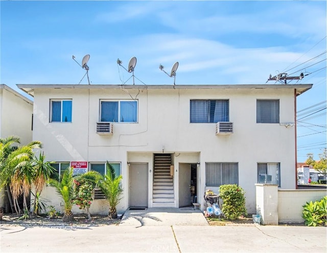 view of front of property with stucco siding and an AC wall unit