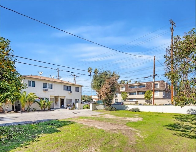 view of front of property featuring stucco siding, a front lawn, and fence