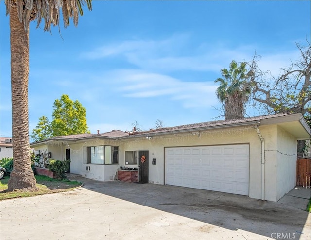 ranch-style house featuring stucco siding, a garage, and driveway