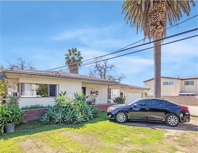 view of front of property with brick siding, stucco siding, a front yard, and a garage