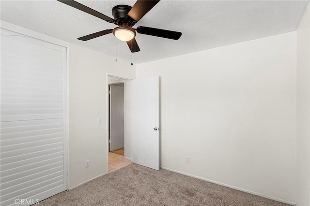 unfurnished bedroom with light colored carpet, a textured ceiling, and a ceiling fan