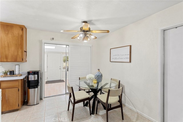 dining space featuring light tile patterned flooring, baseboards, and ceiling fan