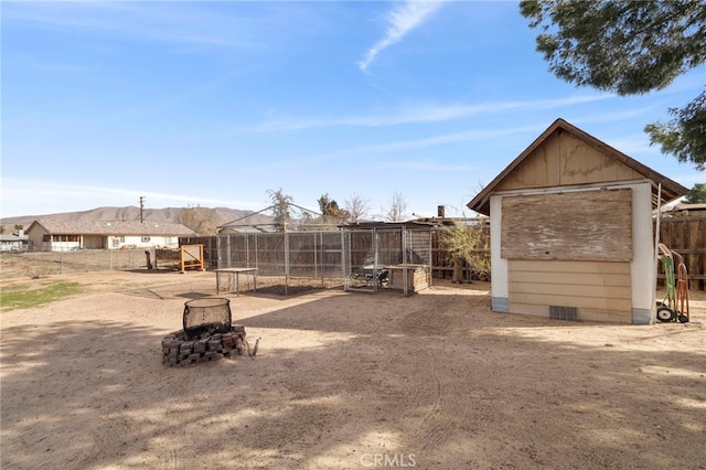 view of yard featuring a fire pit, an outdoor structure, and fence