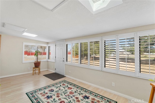 foyer with baseboards, a textured ceiling, and wood finished floors