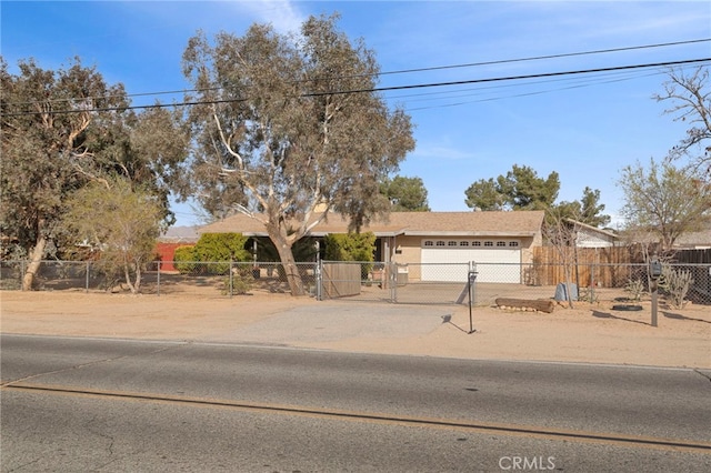 view of front of home with a fenced front yard, concrete driveway, an attached garage, and a gate