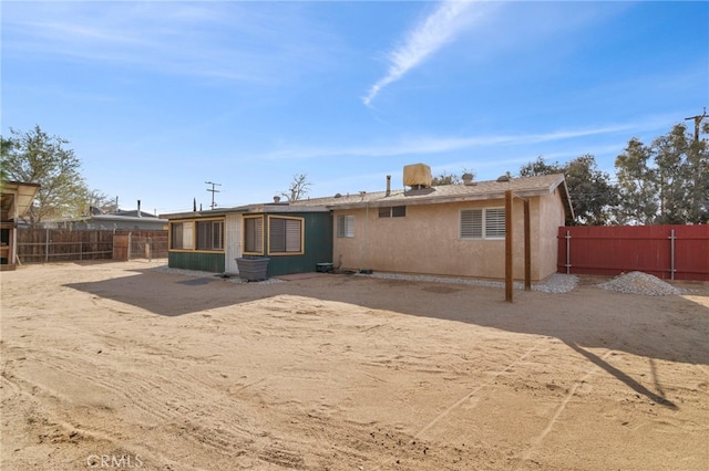 back of house with a fenced backyard and stucco siding