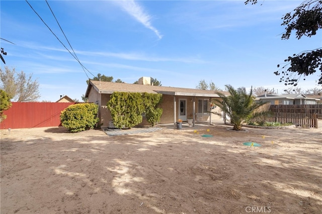 back of property with stucco siding and fence