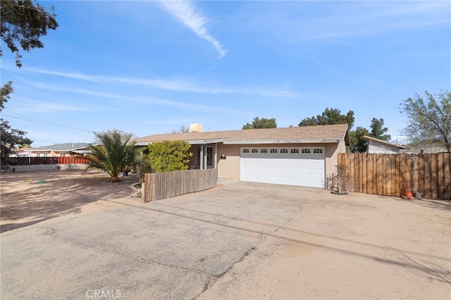 single story home featuring stucco siding, an attached garage, driveway, and fence