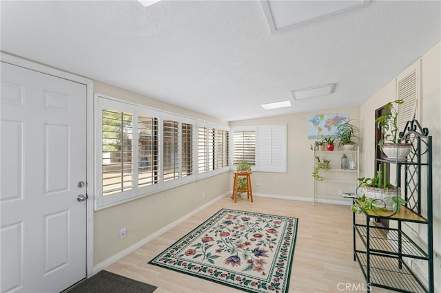 entryway with wood finished floors, baseboards, and a textured ceiling