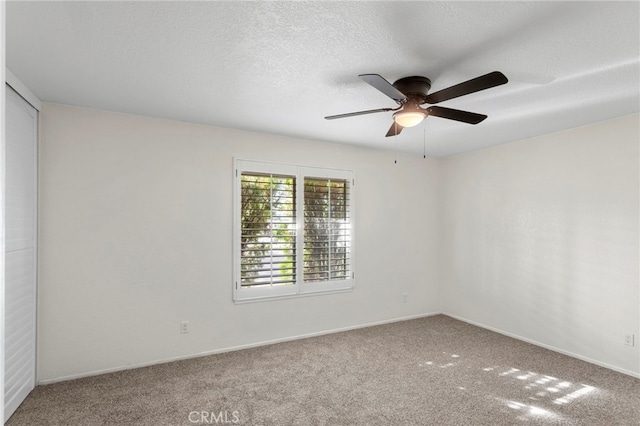 carpeted spare room featuring a ceiling fan, baseboards, and a textured ceiling