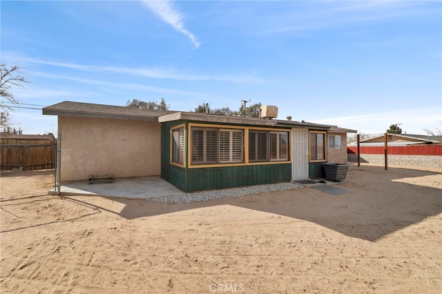 rear view of house with fence and stucco siding