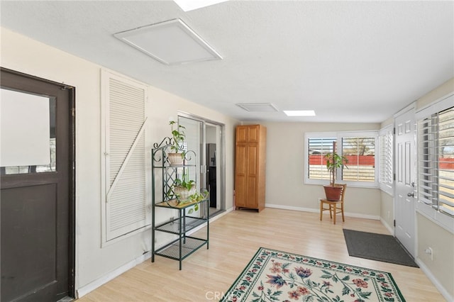 foyer entrance featuring baseboards, a textured ceiling, and light wood-style flooring