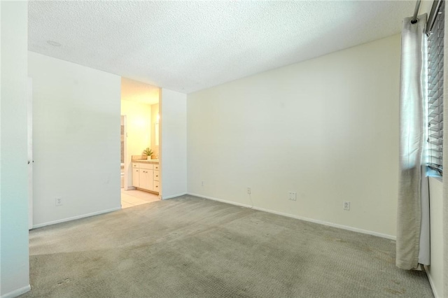27666 Nugget Dr Unit 3, Canyon Country, CA 91387 - unfurnished bedroom featuring light carpet, connected bathroom, baseboards, and a textured ceiling