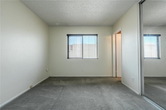 27666 Nugget Dr Unit 3, Canyon Country, CA 91387 - unfurnished bedroom featuring a textured ceiling, multiple windows, carpet floors, a closet, and baseboards