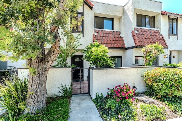 27666 Nugget Dr Unit 3, Canyon Country, CA 91387 - view of front of property featuring a tiled roof, stucco siding, a fenced front yard, and a gate