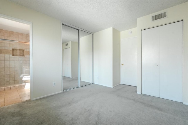 27666 Nugget Dr Unit 3, Canyon Country, CA 91387 - unfurnished bedroom with multiple closets, carpet, ensuite bathroom, a textured ceiling, and tile patterned floors