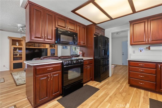 kitchen with light wood-type flooring, black appliances, and light countertops