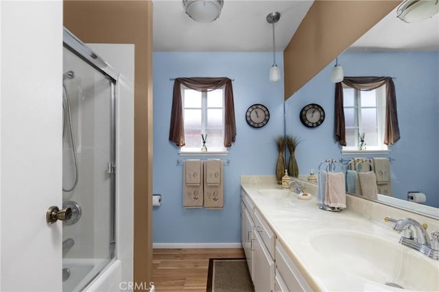 bathroom featuring a sink, baseboards, wood finished floors, and double vanity