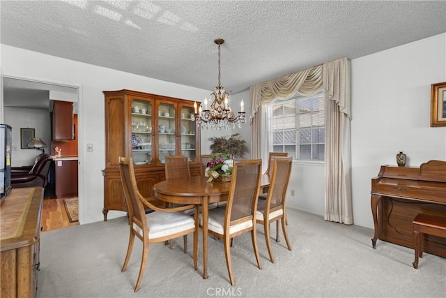 dining room featuring light carpet, a textured ceiling, and an inviting chandelier