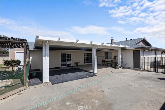 back of property with a patio area, a shingled roof, and fence