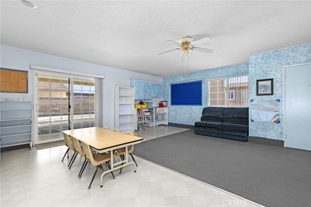 dining room featuring a healthy amount of sunlight, a textured ceiling, and wallpapered walls