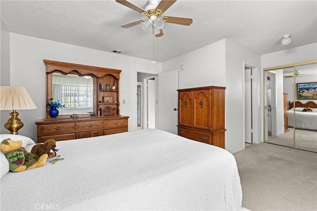 bedroom featuring a textured ceiling, ceiling fan, a closet, and light carpet