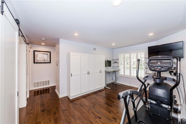 exercise room with a barn door, baseboards, visible vents, and dark wood-style flooring