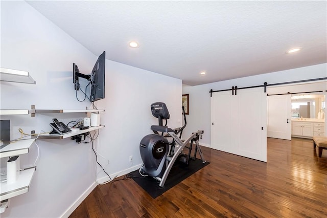 workout area featuring a barn door, recessed lighting, wood finished floors, and baseboards