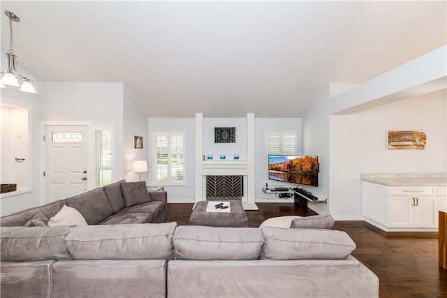 living room with baseboards, a brick fireplace, and dark wood finished floors