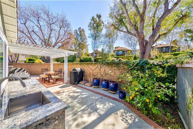 view of patio with area for grilling, a pergola, a sink, a fenced backyard, and outdoor dining area