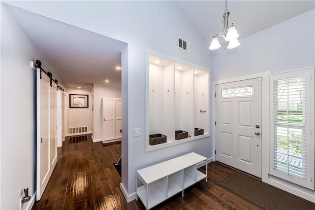 foyer entrance featuring a barn door, visible vents, and dark wood-style floors