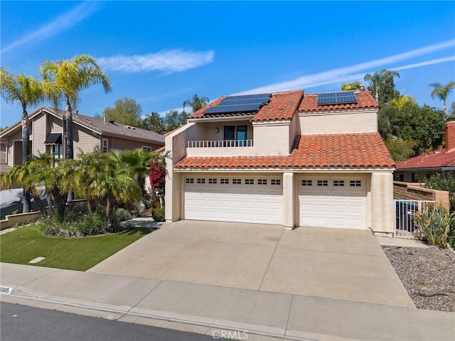 mediterranean / spanish-style house with stucco siding, a tiled roof, concrete driveway, and solar panels