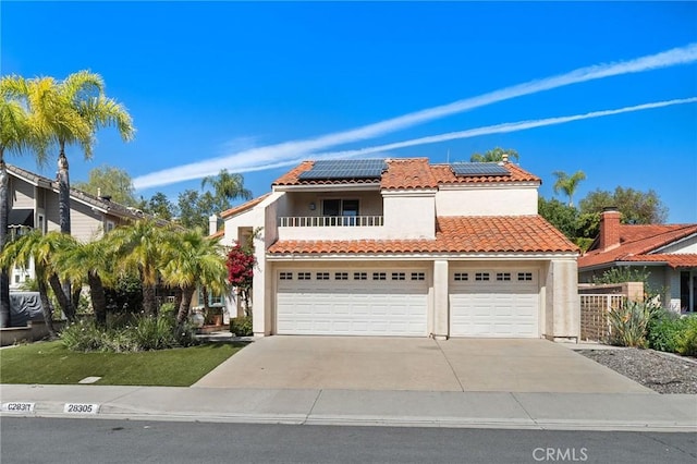 mediterranean / spanish home featuring solar panels, concrete driveway, stucco siding, a balcony, and a garage