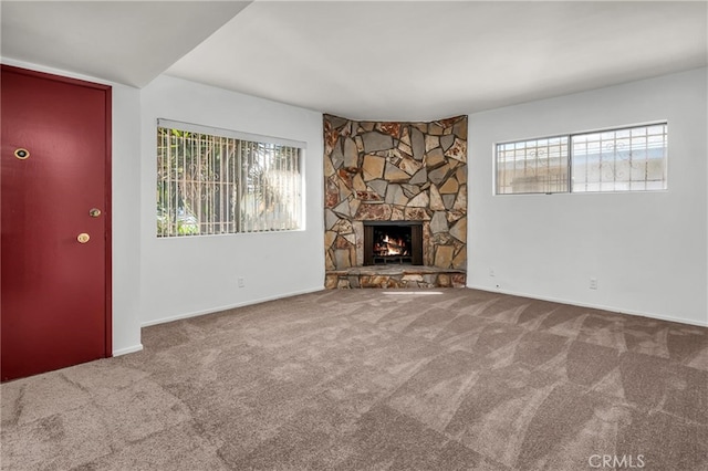 unfurnished living room with a stone fireplace and carpet flooring