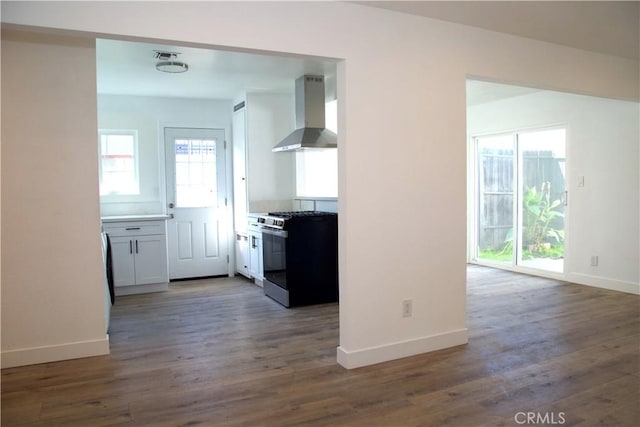 kitchen featuring visible vents, baseboards, stainless steel range with gas stovetop, dark wood-style flooring, and wall chimney range hood