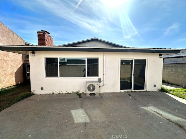 back of house with fence, ac unit, stucco siding, a chimney, and a patio