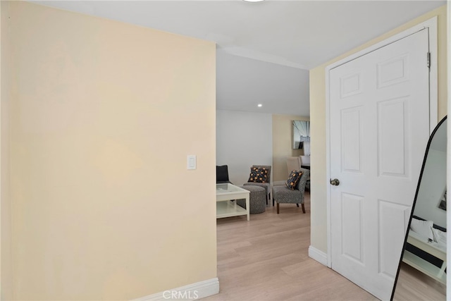 hall featuring light wood-style flooring and baseboards