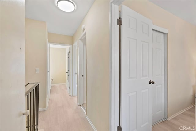 corridor with baseboards and light wood-style flooring