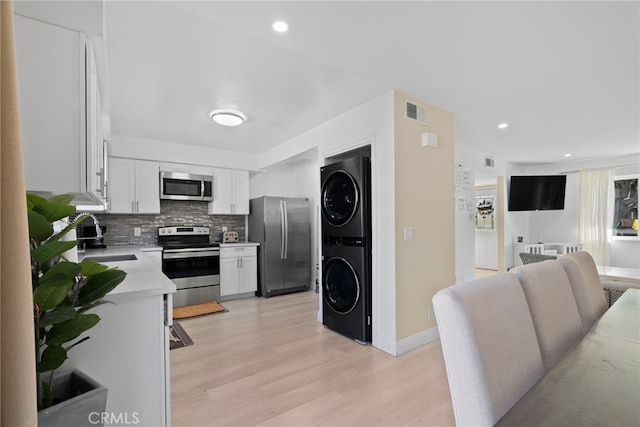 kitchen featuring visible vents, light countertops, stainless steel appliances, stacked washer / drying machine, and a sink