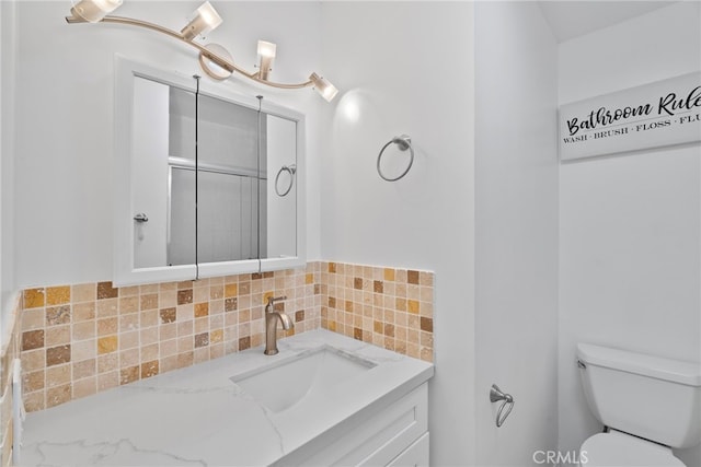 bathroom with vanity, toilet, and tasteful backsplash