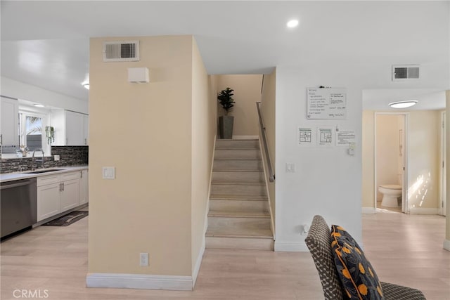 staircase with wood finished floors, visible vents, and baseboards