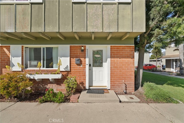 view of exterior entry featuring brick siding