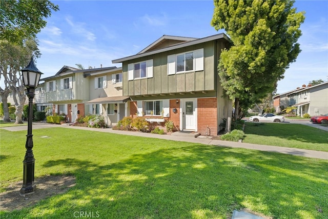 multi unit property with board and batten siding, a front lawn, brick siding, and a residential view