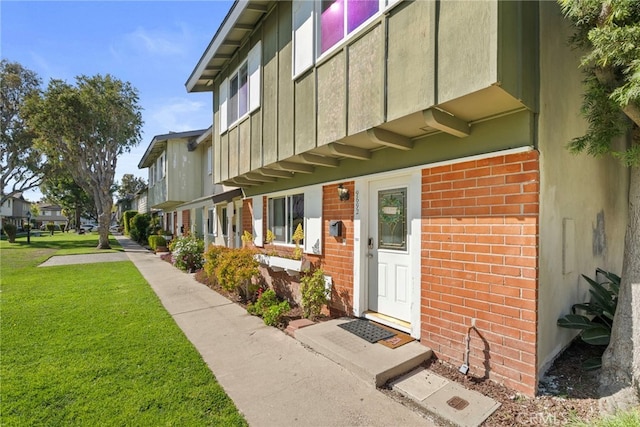 entrance to property featuring a yard, brick siding, and a residential view