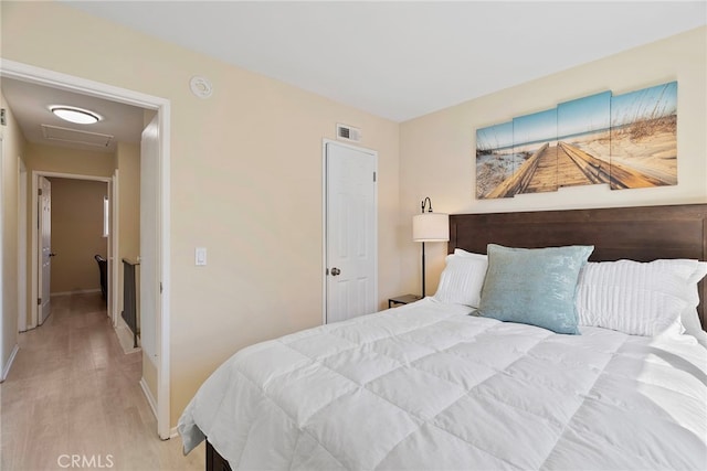 bedroom featuring light wood-type flooring, visible vents, baseboards, and attic access