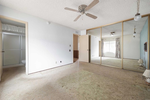 unfurnished bedroom with visible vents, a textured ceiling, a closet, connected bathroom, and carpet flooring