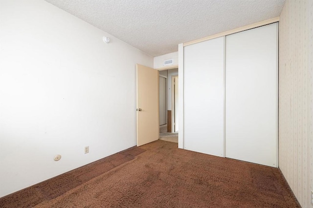 unfurnished bedroom featuring carpet flooring, visible vents, a closet, and a textured ceiling