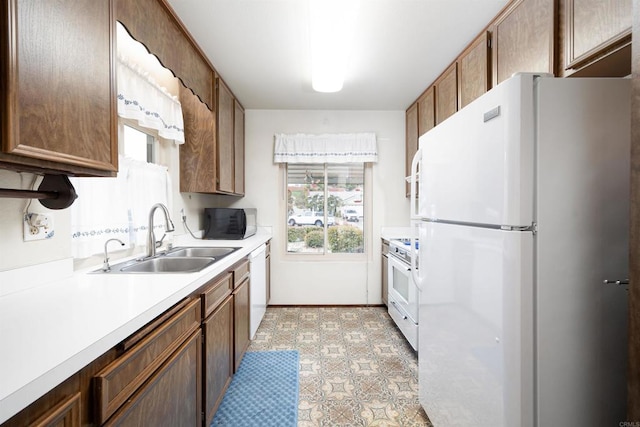 kitchen with white appliances, light countertops, and a sink